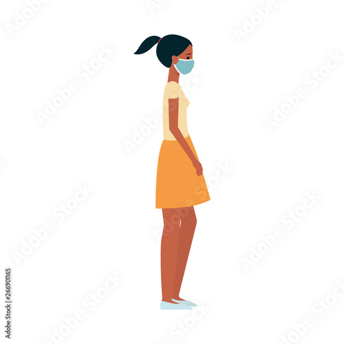 Dark skinned young woman or girl in a skirt and tshirt in a medical protective mask on her face.