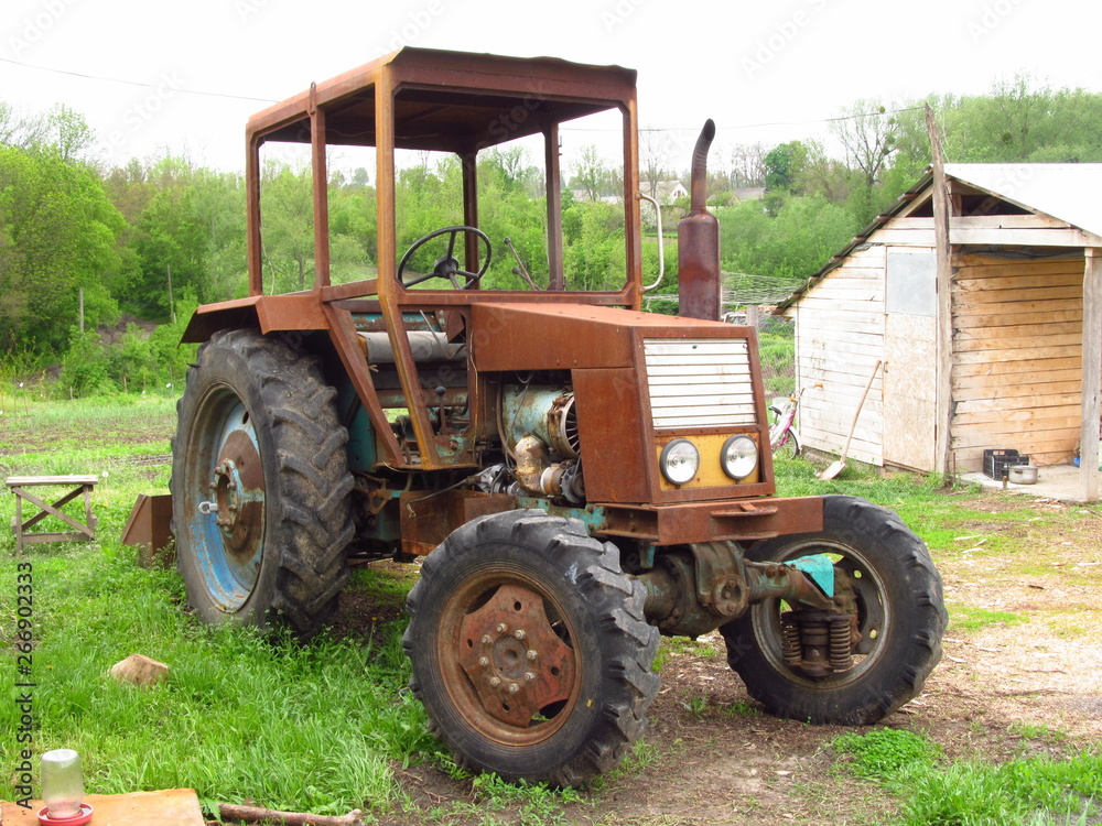 an old tractor, a rusty body, a wooden room, a green courtyard an old tractor, a rusty body, a wooden room, a green courtyard