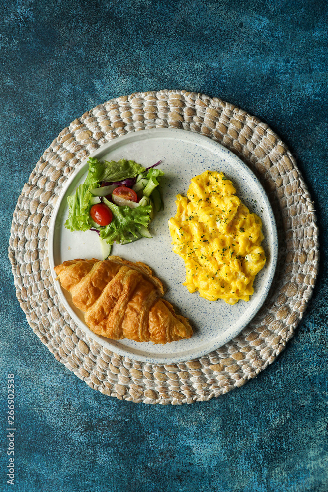 Breakfast with croissant, scrambled egg, and vegetables salad