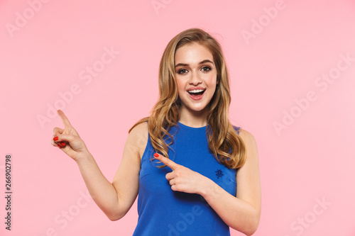 Happy young pretty woman posing isolated over pink wall background showing copyspace. © Drobot Dean