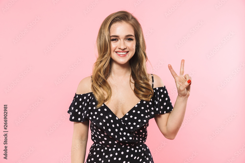 Happy young pretty woman posing isolated over pink wall background showing peace gesture. Happy young pretty woman posing isolated over pink wall background showing peace gesture.