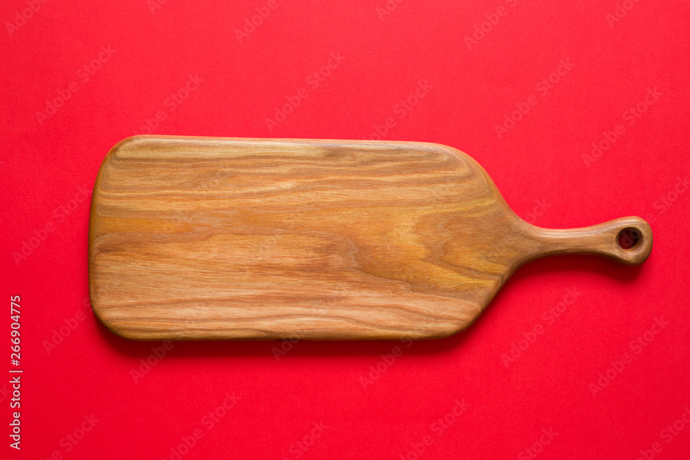 Empty kitchen cutting wooden  board on a red background. Top view.  