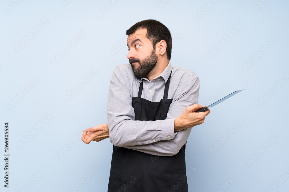 Chef over blue wall making unimportant gesture Chef over blue wall making unimportant gesture