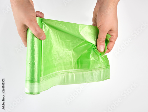 female hand unwind green roll with plastic bags for garbage