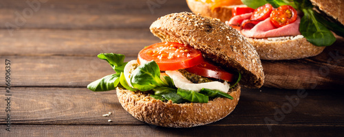 Slika na platnu Italian Caprese sandwiches with fresh tomatoes, mozzarella cheese and lamb's lettuce, multigrain bun