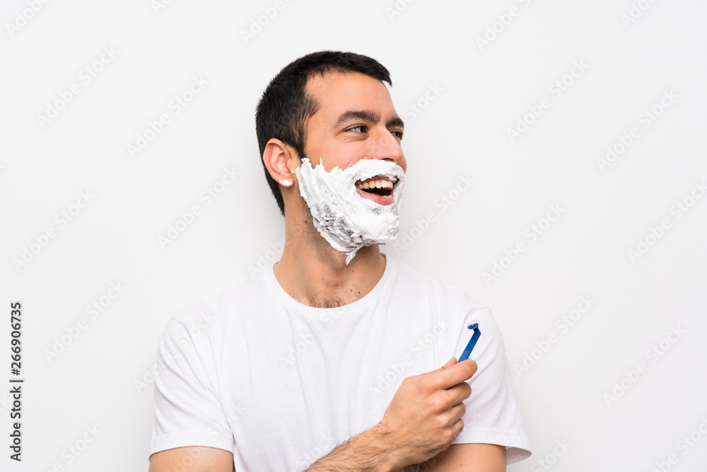 Man shaving his beard over isolated white background happy and smiling