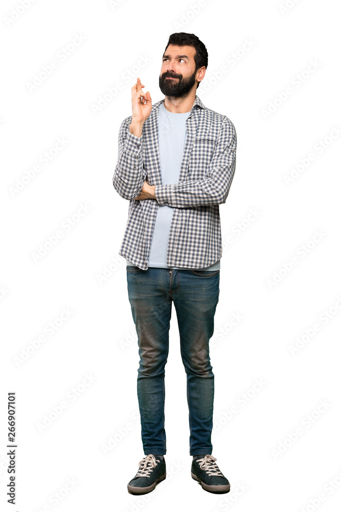 Handsome man with beard with fingers crossing and wishing the best over isolated white background
