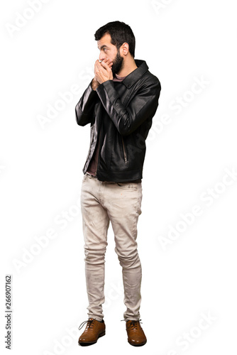 Handsome man with beard covering mouth and looking to the side over isolated white background © luismolinero