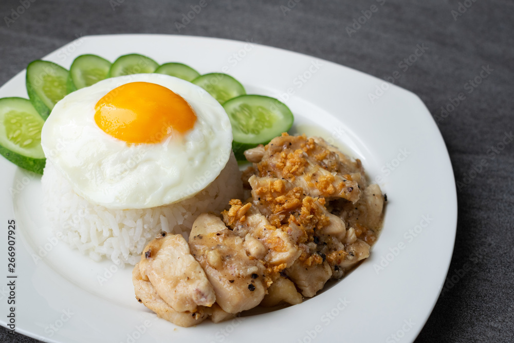 Rice,Fried egg,Fried chicken with garlic and black pepper in white dish on the concrete table. Rice,Fried egg,Fried chicken with garlic and black pepper in white dish on the concrete table.