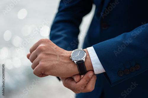 Foto A man in a business suit checking a wrist watch on his hand on background  sea