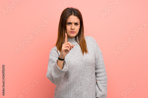 Young woman over pink wall frustrated and pointing to the front