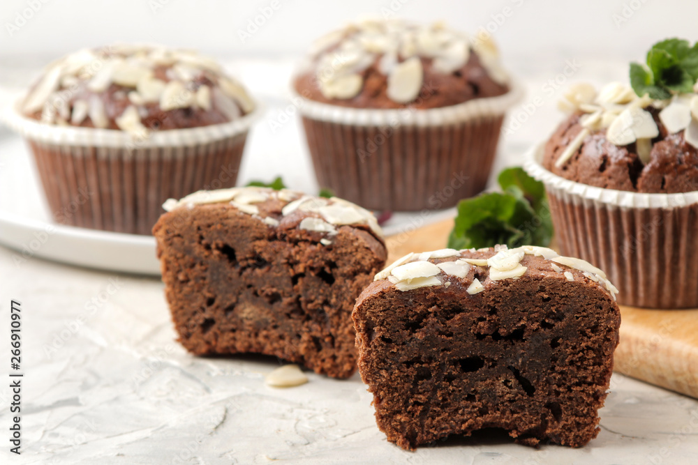 Delicious, sweet chocolate muffins, with almond petals next to mint and almond nuts on a light concrete table. close-up