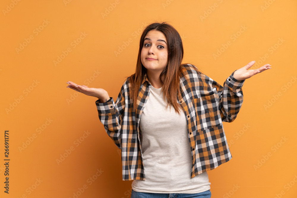 Young woman over brown wall making doubts gesture Young woman over brown wall making doubts gesture