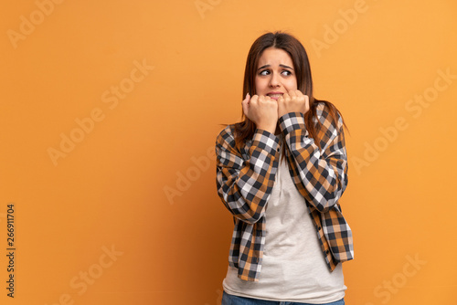 Young woman over brown wall nervous and scared putting hands to mouth © luismolinero