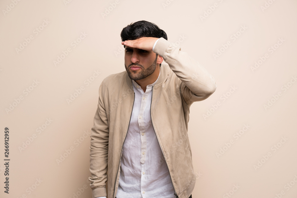 Fototapeta premium Young man over isolated wall looking far away with hand to look something