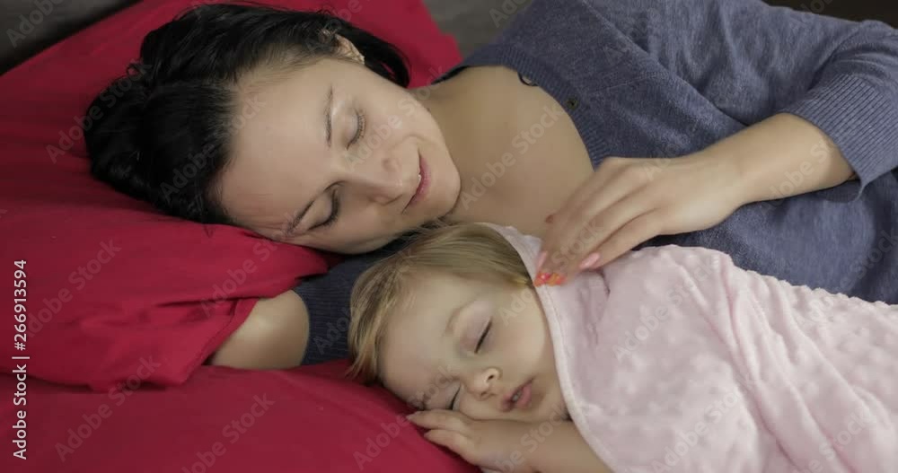 Young mother sleeping with her little baby daughter. Family sleeping on the bed Young mother sleeping with her little baby daughter. Family sleeping on the bed