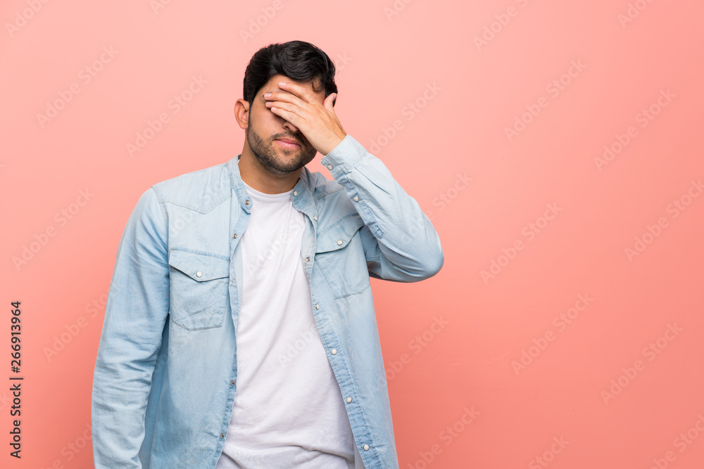 Young man over pink wall covering eyes by hands. Do not want to see something Young man over pink wall covering eyes by hands. Do not want to see something