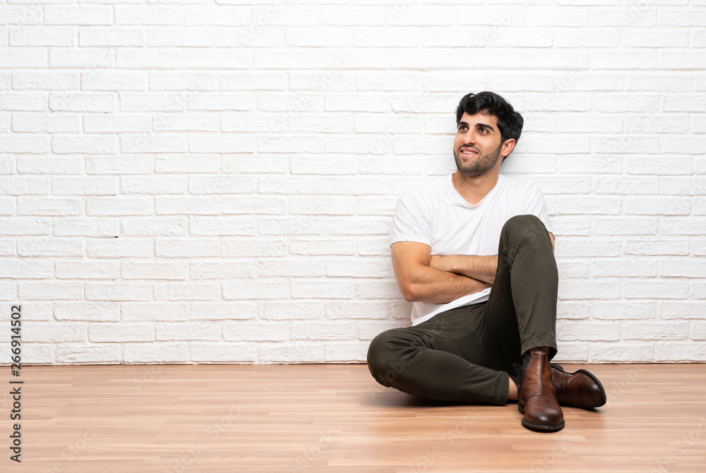 Young man sitting on the floor happy and smiling Young man sitting on the floor happy and smiling