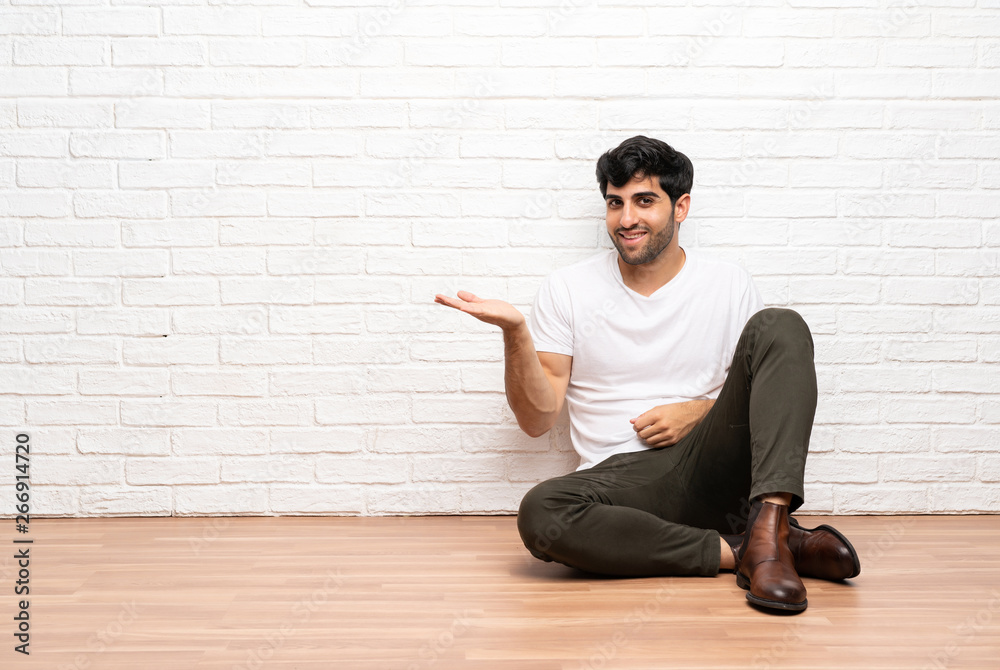 Young man sitting on the floor presenting an idea while looking smiling towards