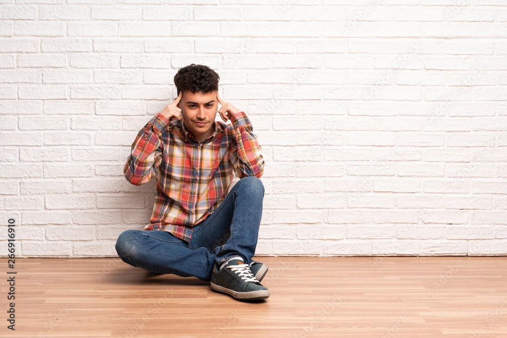 Young man sitting on the floor having doubts and thinking