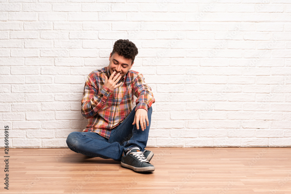 Young man sitting on the floor smiling a lot Young man sitting on the floor smiling a lot