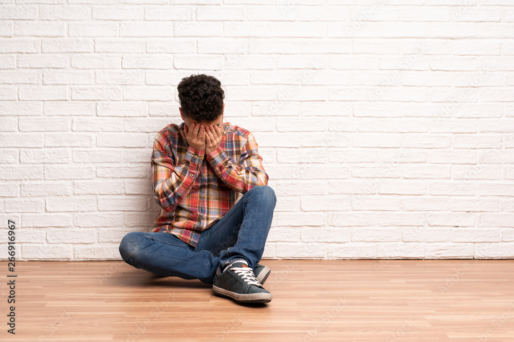 Young man sitting on the floor with tired and sick expression Young man sitting on the floor with tired and sick expression