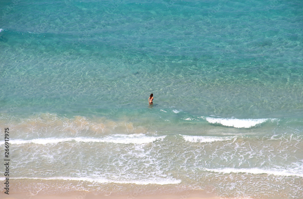 Young slim woman in blue sea. Top view turquoise transparent water
