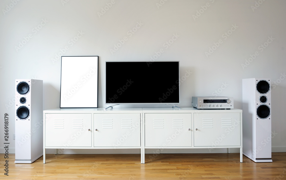 Poster on table in room.Modern audio stereo system with white speakers on bureau in modern interior