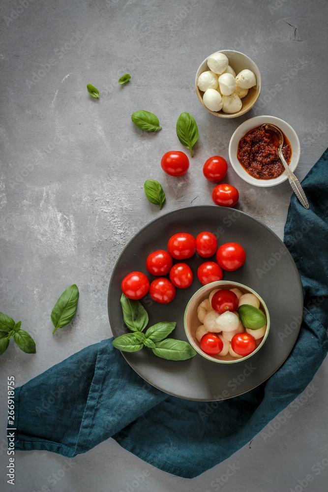 Small bowls with colorful ingredients of Caprese salad on a dark background, flat lay style Small bowls with colorful ingredients of Caprese salad on a dark background, flat lay style