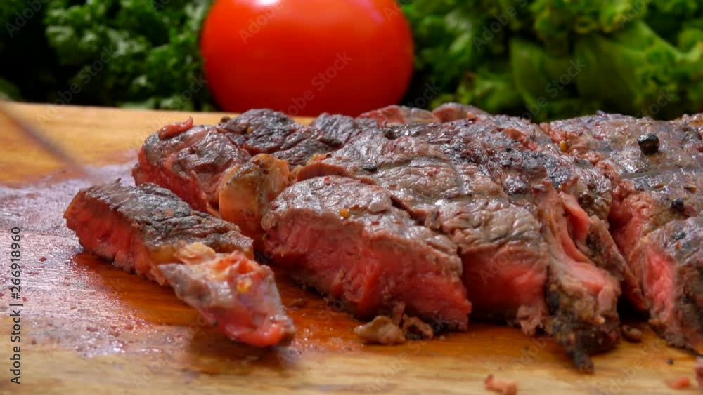 The chef turns the finished juicy steak on a wooden board with a table knife The chef turns the finished juicy steak on a wooden board with a table knife
