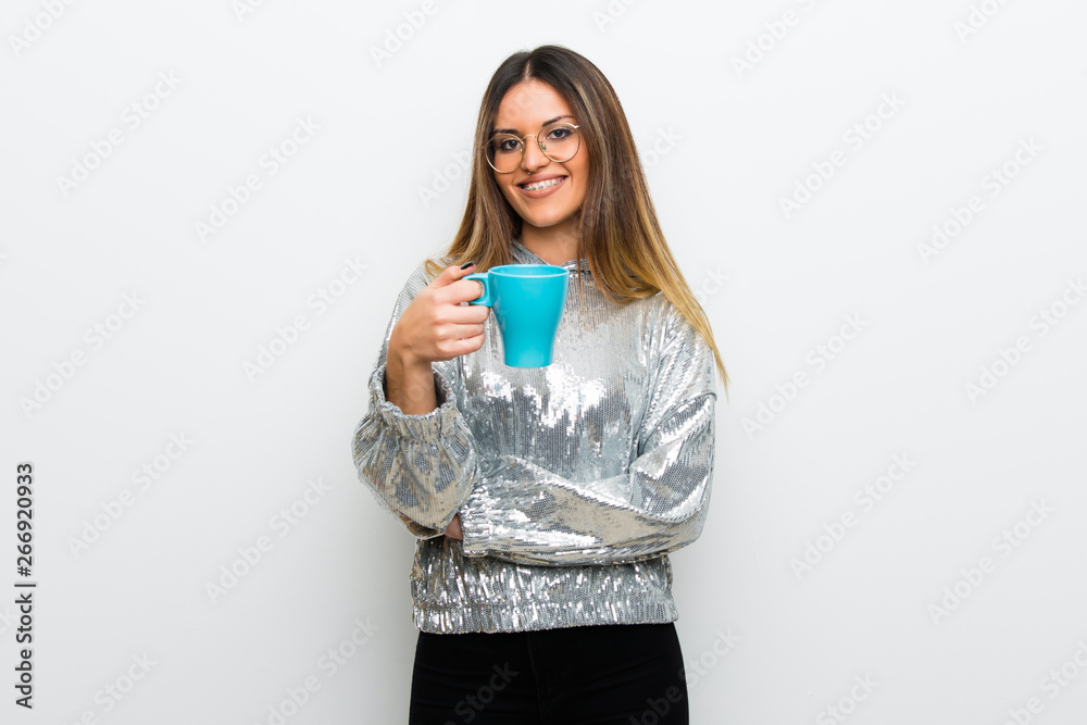 Young woman with glasses over white wall holding a hot cup of coffee Young woman with glasses over white wall holding a hot cup of coffee