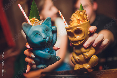 Tiki Drink Cocktails. Tropical tiki cocktails man and woman are holding. photo