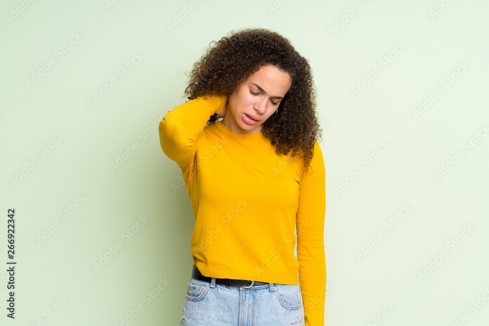 Dominican woman over isolated green background with neckache