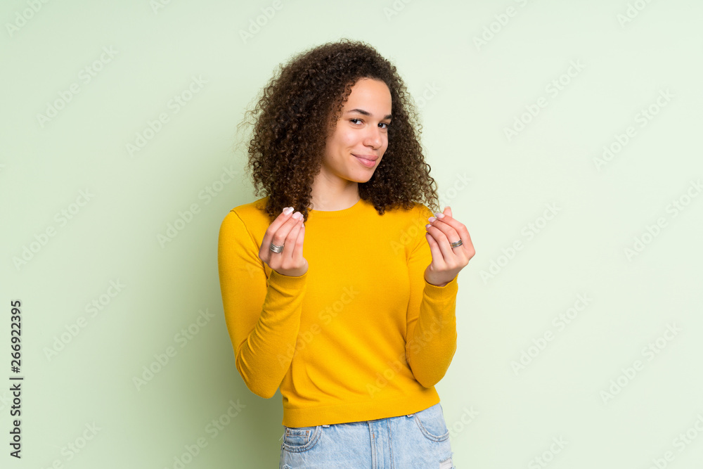 Dominican woman over isolated green background making money gesture Dominican woman over isolated green background making money gesture