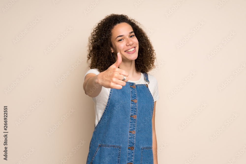 Dominican woman with overalls with thumbs up because something good has happened Dominican woman with overalls with thumbs up because something good has happened