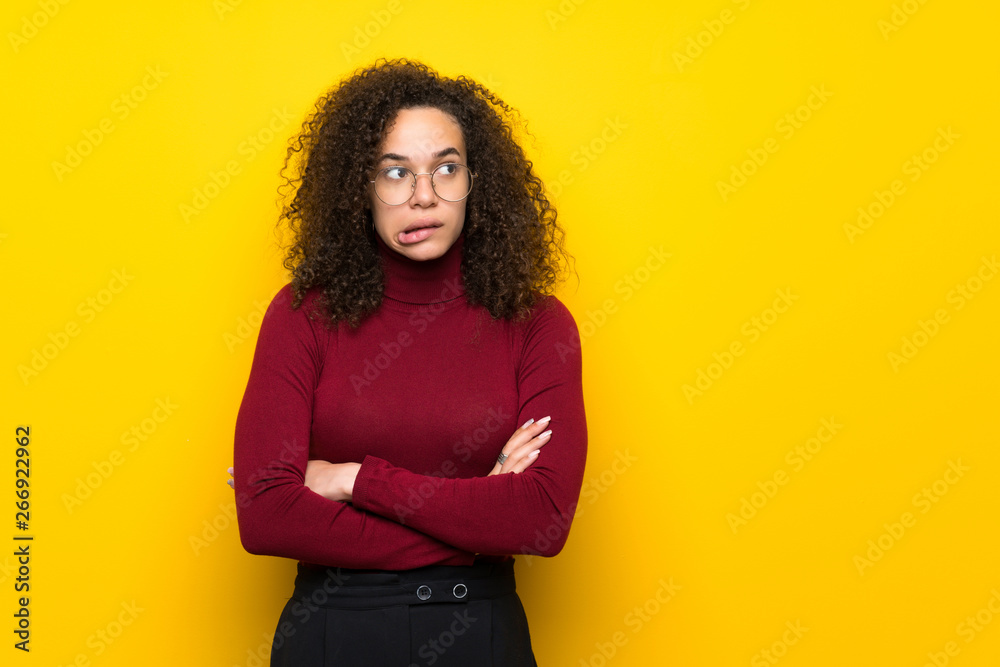 Dominican woman with turtleneck sweater with confuse face expression while bites lip Dominican woman with turtleneck sweater with confuse face expression while bites lip