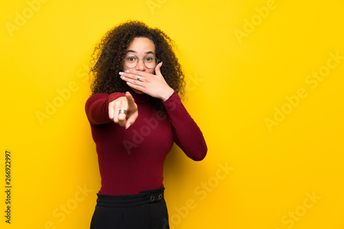 Dominican woman with turtleneck sweater pointing with finger at someone and laughing