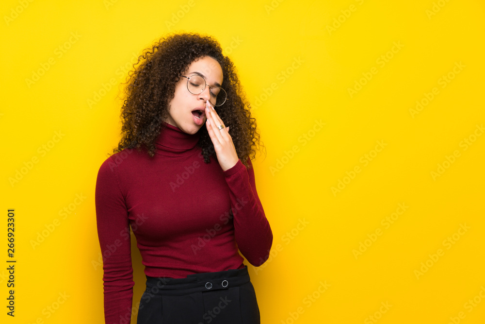 Dominican woman with turtleneck sweater yawning and covering wide open mouth with hand Dominican woman with turtleneck sweater yawning and covering wide open mouth with hand