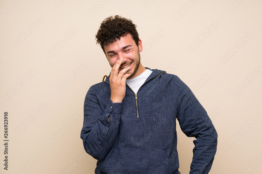 Man with curly hair over isolated wall smiling a lot