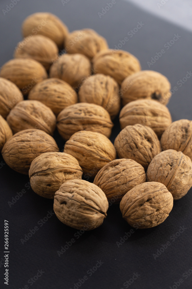 Walnuts in shell lying on black surface, side view. Healthy nuts and seeds background.