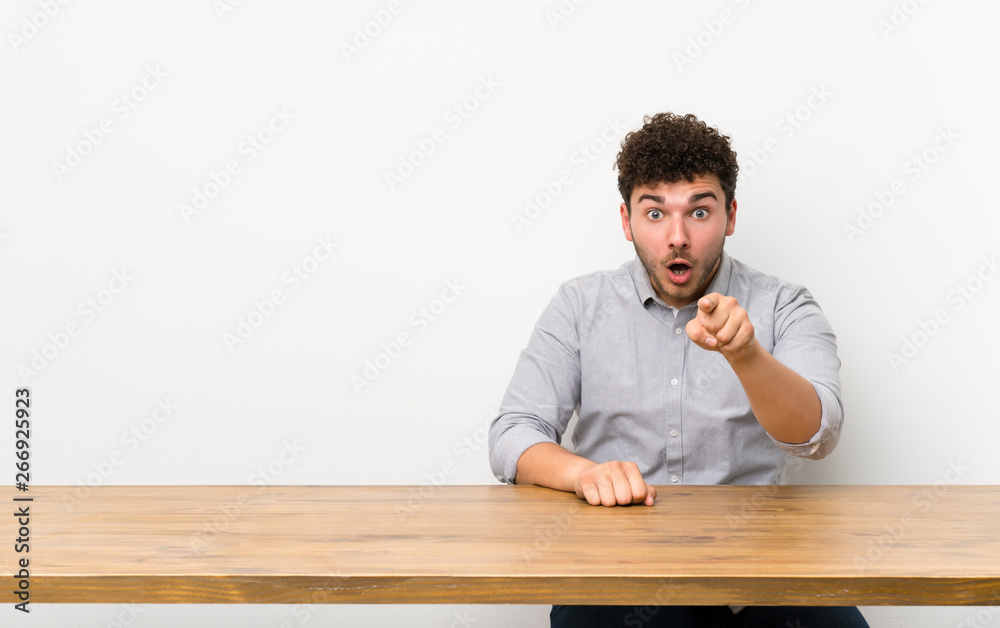 Young man with a table surprised and pointing front Young man with a table surprised and pointing front