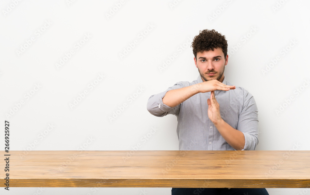 Young man with a table making time out gesture Young man with a table making time out gesture