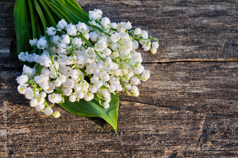 Bouquet of the lily of the valley flowers on a wooden background Bouquet of the lily of the valley flowers on a wooden background