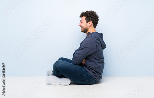 Young man sitting on the floor in lateral position © luismolinero