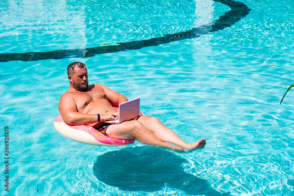 Dream job, a young man with a computer in the water on an inflatable circle,Man with a laptop on inflatable ring in the water