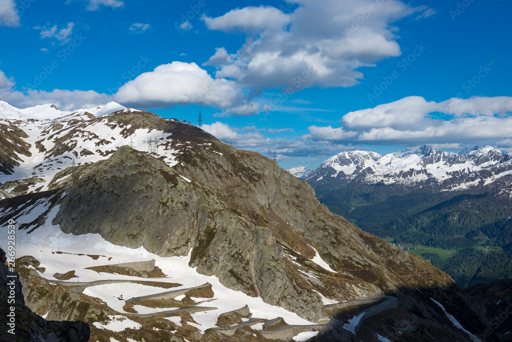 Obraz premium Mountain Road St: Gotthard Pass and Snow-capped Mountain With Blue Sky and Clouds in San Gottardo, Switzerland.