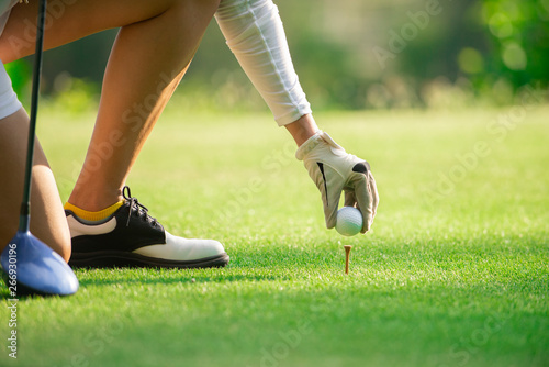 Close up on woman golfer hand putting golf ball on tee at golf course ,Healthy Holiday Concept