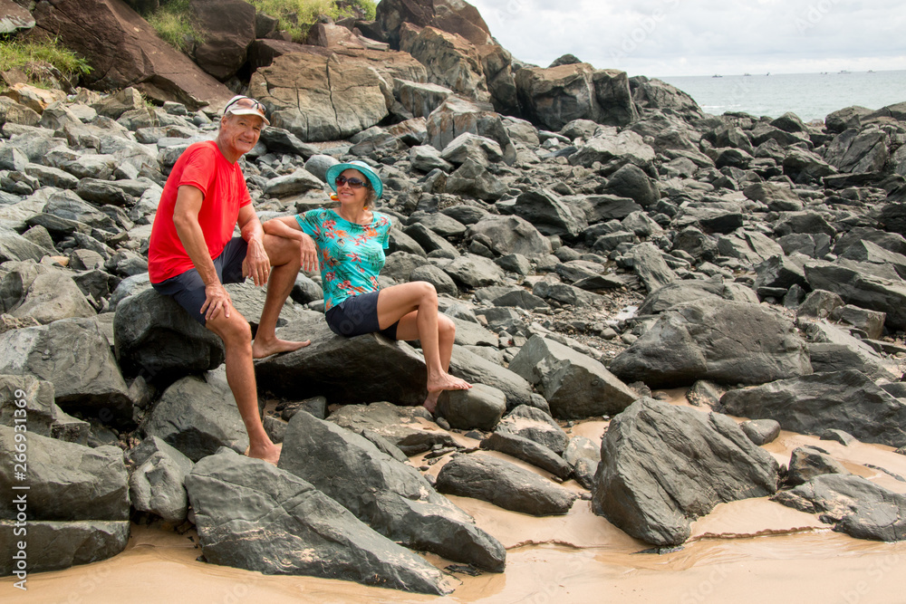 Mature Couple Sitting at a Rocky Beach Enjoying Each Other Mature Couple Sitting at a Rocky Beach Enjoying Each Other