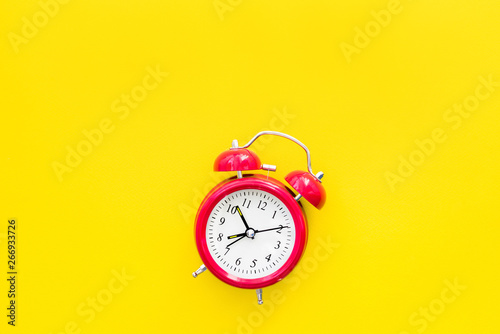 Red vintage alarm clock on a yellow background, top view