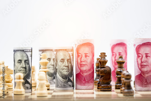 US dollar and Yuan banknote with chess for tariff trade war between United States and China which both countries battle by increase tax barrier of import and export product. Government and business. photo